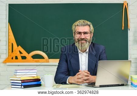 Teach And Inspire. Senior Teacher Sit At Desk. Bearded Man Back To School. Formal Education. Educati