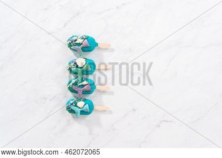 Flat Lay. Mermaid Cakesicles With Drizzled Chocolate, Chocolate Mermaid Tails, Seashells, And Sprink