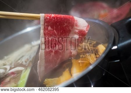 Hand Using Chopsticks Pick Premium Raw Beef Sliced Beef Over The Hot Pot Soup For Shabu Shabu Or Suk
