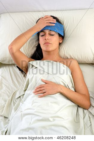 Päänsärky nainen sängyssä tilalla icepack.