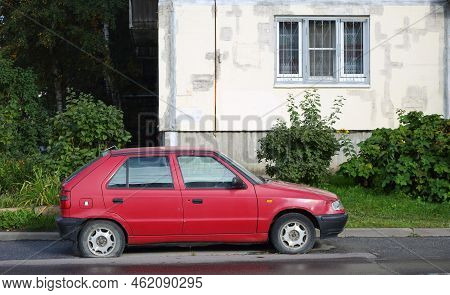 An Old Red Car With A Flat Tire Stands Near A Residential Building, Antonova-ovseenko Street, St. Pe