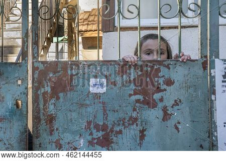 Jerusalem, Israel - July 7th, 2022: An Orthodox Jewish Boy Looking Out Behind The Gates Of His Commu