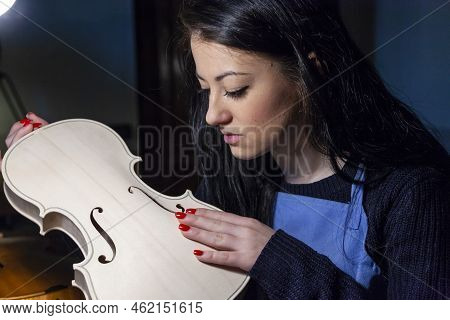Young Woman Apprentice Violinmaker Checking Her Violin