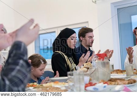 Muslim family making iftar dua to break fasting during Ramadan.