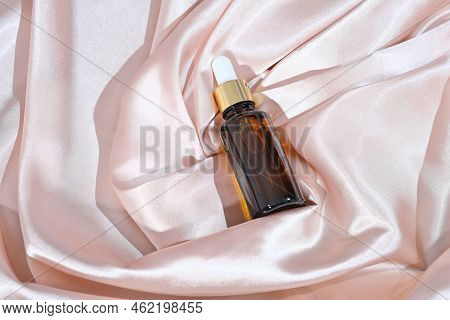 Amber Glass Dropper Bottle With Cosmetic Product On A Satin Or Silk Background. Beauty Face Care Sol