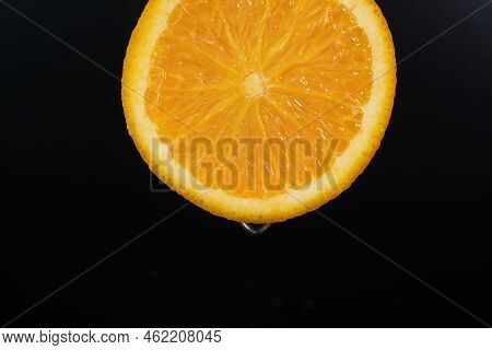 Water Drop Falling From Orange Hue Orange On Black Background. Orange Slice And Water Splashing, Dro