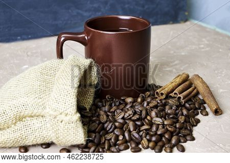 Coffee Beans Spilled Out Of A Canvas Bag Of Cinnamon And A Coffee Mug Onto A Table With A Place Of C