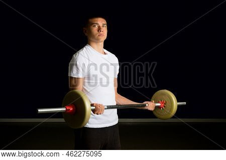 19 Year Old Teenage Boy Excercising His Biceps With A Barbell