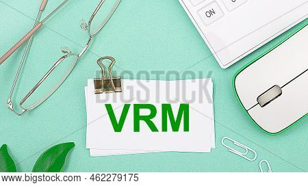 On A Light Green Background There Is A White Calculator, A Computer Mouse, Green Leaves Of A Plant, 