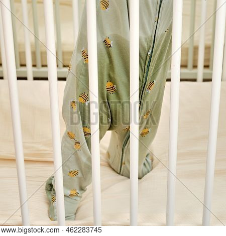 Toddler Baby With Wet Pants Due To A Leaking Diaper Stands In A Crib After A Night Sleep