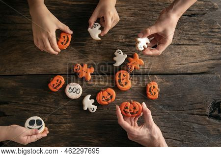 Festive Gingerbread On Halloween In Form Of Ghosts, Pumpkins And Ginger Man In Childrens Hands On Wo