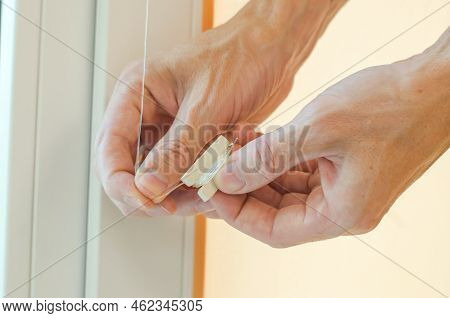 Close-up Of Male Hands Installing Roller Blinds On The Window. Installation Of Roller Blinds