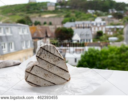 French Heartshaped Neufchatel Cow Cheese On White Paper And View On Old Houses Of Etretat, Normandy,