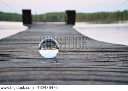 Glass Ball On A Wooden Walkway On A Swedish Lake At The Blue Hour. Nature Shot From Scandinavia