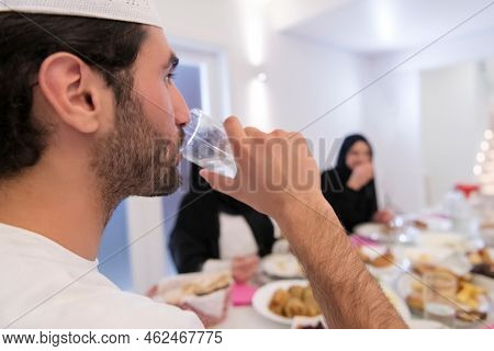 Muslim family making iftar dua to break fasting during Ramadan.