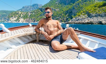 Young Man Relaxing On A Wooden Boat During A Boat Trip To Butterfly Beach At Fethiye Turkey,