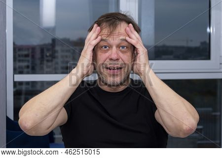 Emotional Portrait Of An Elderly Man Of 45-50 Years Old In A Black T-shirt, Holding His Hands To His