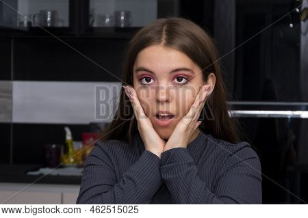 Emotional Portrait Of A Young Girl On A Neutral Background In A Room, Holding Her Hands Behind Her H