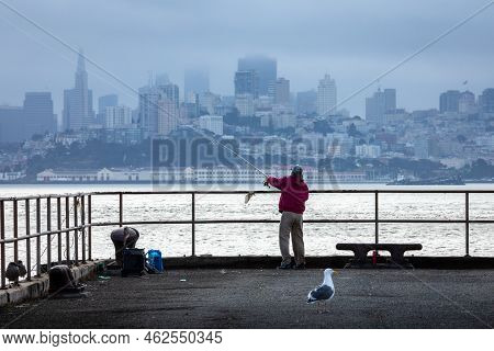 San Francisco, California, Usa - September 27, 2019: Senior Woman In Red Jacket Trowing A Fish Rod I