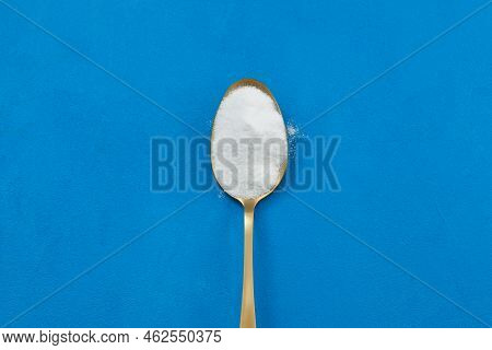 Gold Spoon With White Powder, Close-up. Dietary Supplement Or Sports Nutrition. Blue Background, Pla