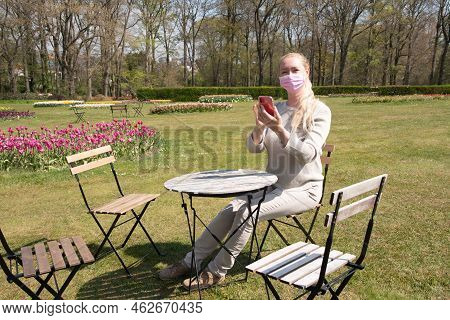 Young Woman In A Protective Mask Takes A Selfie With Blooming Sprimg Tulips