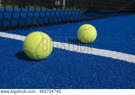 Two Balls Near The Net Of A Paddle Tennis Court