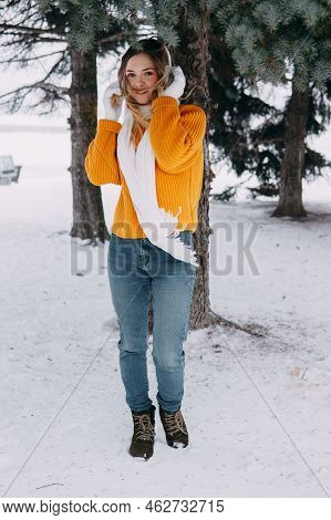Teen Blonde In A Yellow Sweater Outside In Winter. A Teenage Girl On A Walk In Winter Clothes In A S