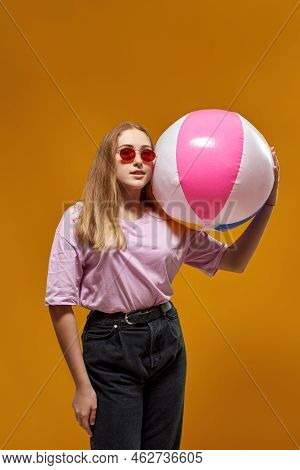 Caucasian Female Teenage With Beach Ball Looking At Camera. Girl Of Zoomer Generation Wearing Sungla