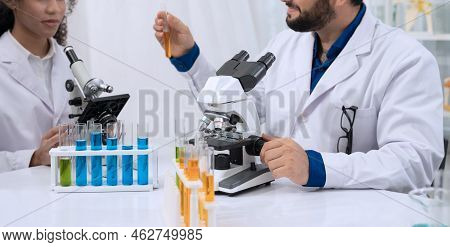 Two Scientist Researchers Wearing White Coat And Working In Laboratory. Man Holding Test Tube With Y