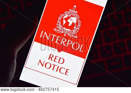 Person Holding Smartphone With Interpol Logo Displayed On Screen.