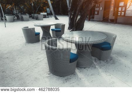 A Wide-angle View With A Selective Focus On The Group Of Empty Outdoor Wicker Cafe Tables On The Cor