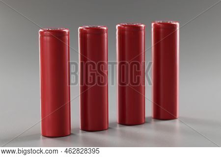 Red Batteries Stand In A Row On A Gray Background, Close-up. Rechargeable Alkaline Battery. Disposal
