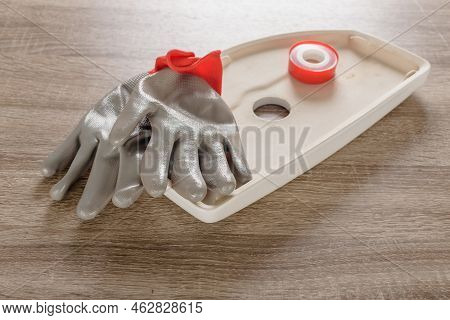 Professional Plumber Gloves And Tape Fum Lying On Toilet Lid