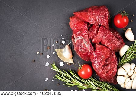 Chopped Raw Beef Or Lamb Meat With Seasonings And Vegetables Over Dark Concrete Background With Copy