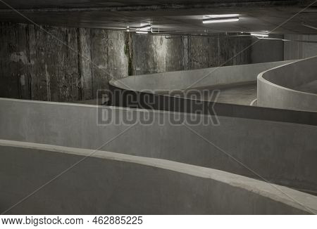 Way Down To Underground Car Parking. Perspective View Of Curving Shaped Ramp Of The Basement Made Of