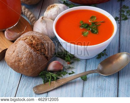 Close-up Of White Ceramic Bowl With Tomato Puree Soup, Rye Bun, Garlicky, Parsley And Vintage Spoon.