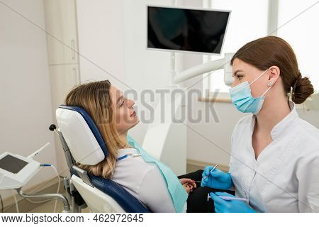 Dentist Talking To A Client.side View Of A Female Dentist Giving Advice And A Female Client Sitting 