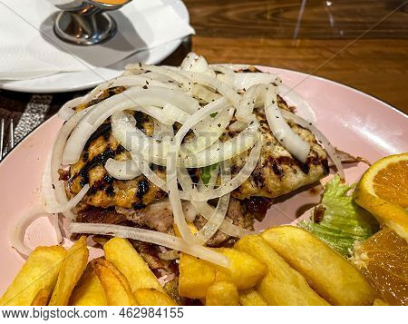 A Greek Dish With A Variety Of Meats, Chips And Onions.