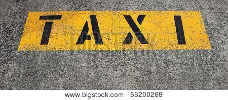 The term taxi written on the asphalt marking a taxi rank.
