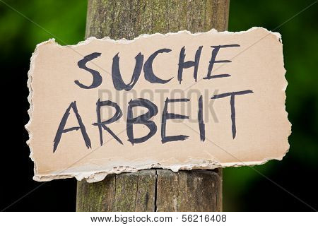 Cardboard sign showing the german term Suche Arbeit. English translation: looking for a job