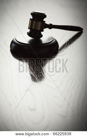 Dramatic Gavel Silhouette on Reflective Wood Surface.