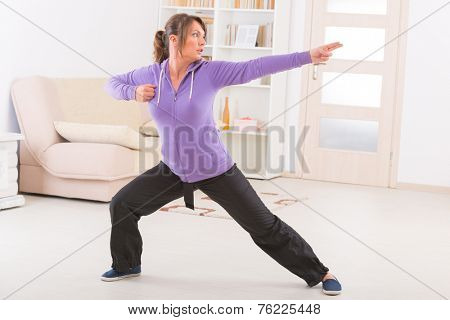 Beautiful woman doing qi gong tai chi exercise at home