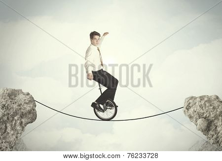 Brave business man riding an mono cycle between cliffs concept
