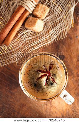 A cup of spiced coffee with anis star and cinamon sticks and sugar