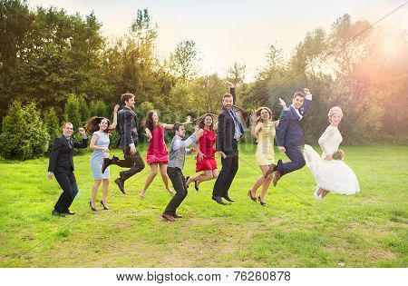 Newlyweds with guest jumping in park