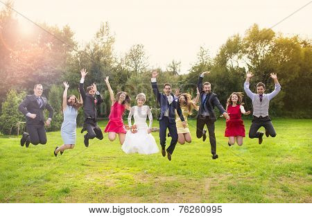 Newlyweds with guest jumping in park