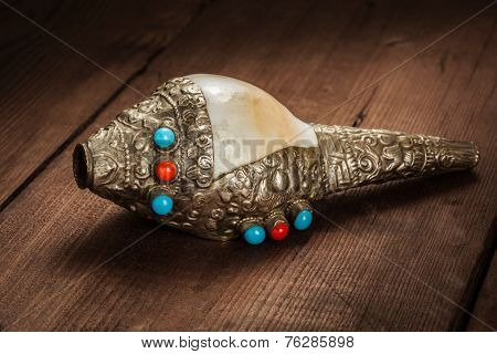Tibetan Buddhist Conch Shell Horn Dung-Dkar on wooden background