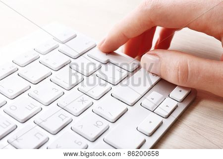 Female hand with keyboard on wooden desktop background