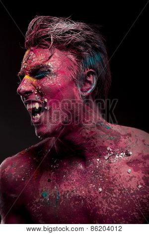 A creepy portrait of man with red body art.