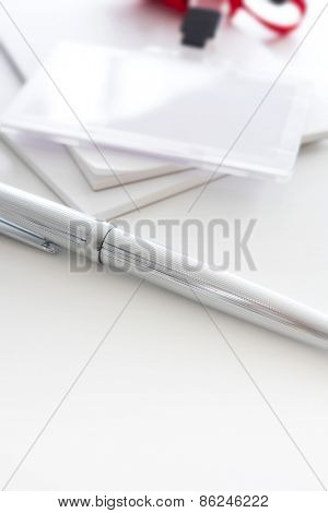 Silver pen and security or ID card with red strap. Shallow depth of field.
